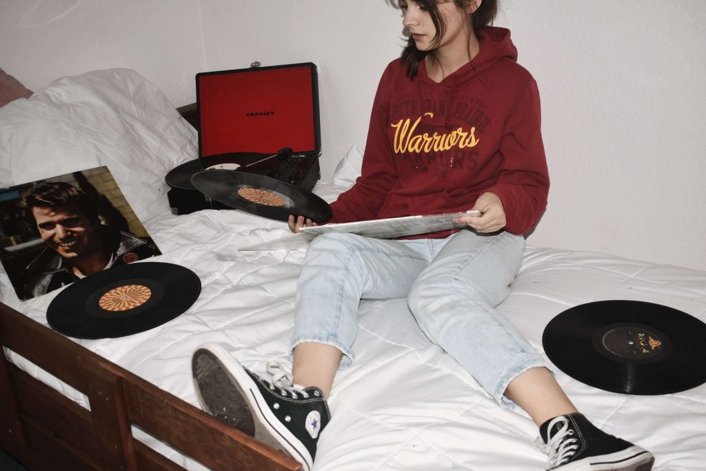 girl sitting on her bed with vinyl records